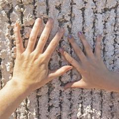 Hands on textured concrete on a building exterior