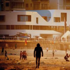 Man on beach walking towards Le Corbusier building